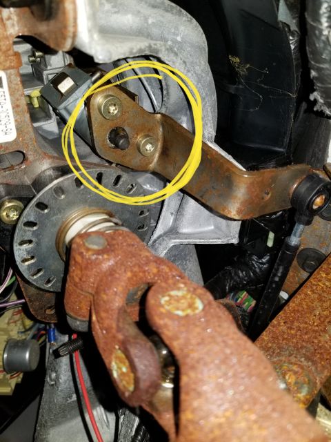 1995 Ford Bronco - A close-up view of rusty steering column components, including a bracket secured by two Torx screws and a black plastic electrical connecto…