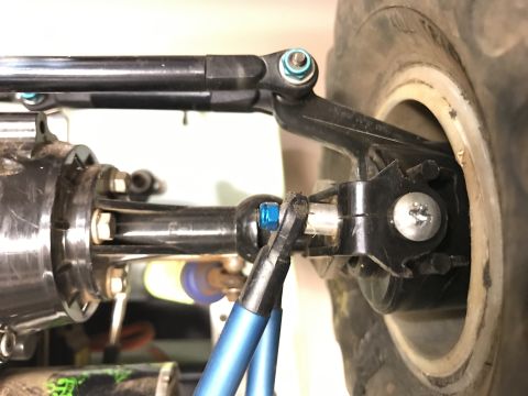 1989 Ford Bronco - A close-up view of the suspension and steering components of an off-road vehicle. Visible parts include a black steering linkage, a blue ti…