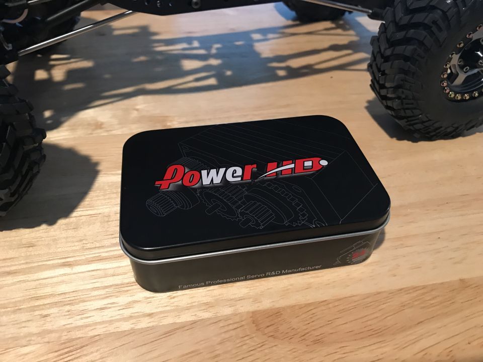 Black tin box with "Power HD" logo and gear illustration on a wooden table.