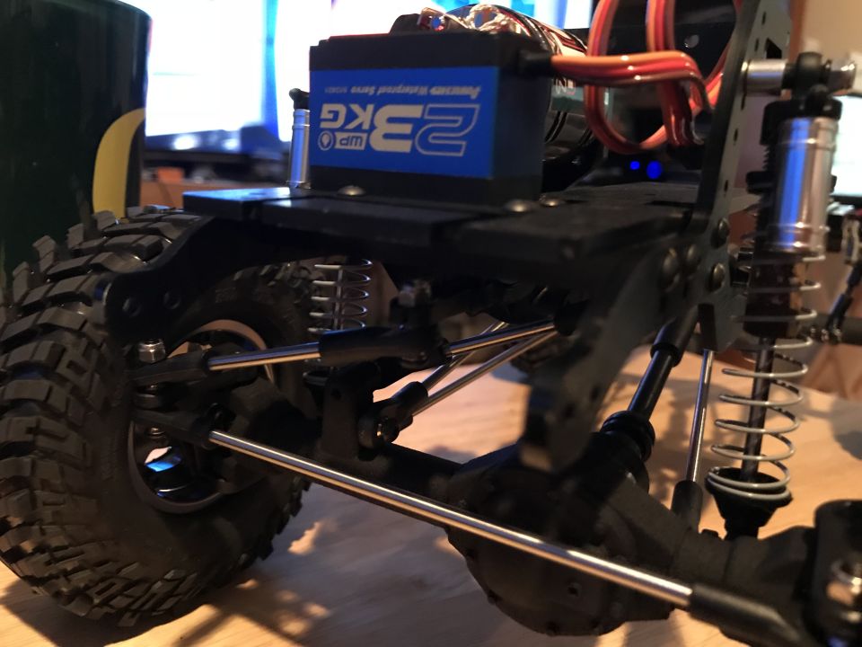 RC vehicle suspension and drivetrain with blue servo motor and silver shock absorber.