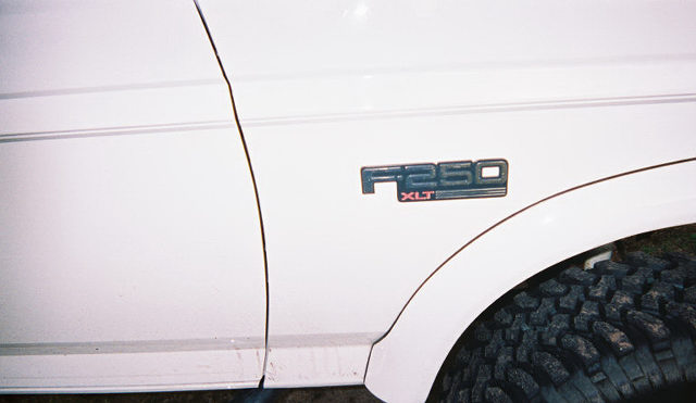White Ford F-250 XLT fender badge above off-road tire