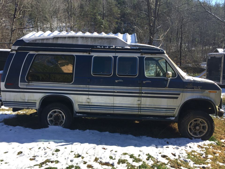 1988 Ford E350 van, side view, dark blue and white, with snow on the roof and aftermarket wheels.