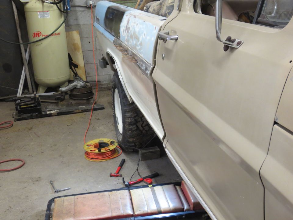 Side view of a tan pickup truck in a garage with tools and equipment.