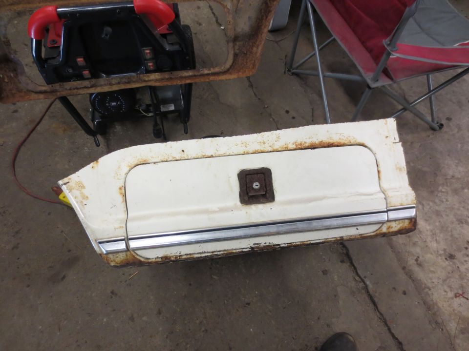 White truck door panel with chrome trim and square latch, showing rust.