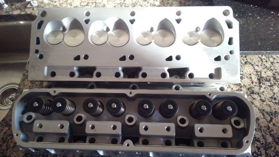 These are a set of unbranded aluminum bare cylinder heads i got on ebay. They were said to have part number AP-330803-8567 tho its not marked anywhere on the heads and claimed to have interchange parts number of Speedmasters PCE281.1556 heads. i bought them for $175 each with free shipping. so $350 for both at my door. 

they are 190cc intake runner size. they have a 62cc chamber size. intake valve is 2.02 and exhaust is 1.60 size. they have 1/2 inch head bolt holes and came with bushings for 7/16 bolts.

i bought these bare and had a local machine shop inspect and assemble them. they told me that the heads were defiantly not square so a resurfacing was done but everything else seemed fine. it may have decreased the chamber size by a small amount. they shop put in some stainless valves and lapped the valves to ensure sealing.a basic roller valve spring kit was installed. they said the springs will be able to handle -low 5s of lift- as they said. not 100 percent sure how much i can get away with but with such large valves i dont need much lift anyways.

the machine shop charged me $489 total. the valves were $11 each so $176 for all 16. they charged me $148  for the valve spring kit including retainers and locks. valve lapping and assembly cost me $75 and the resurfacing cost me $90.