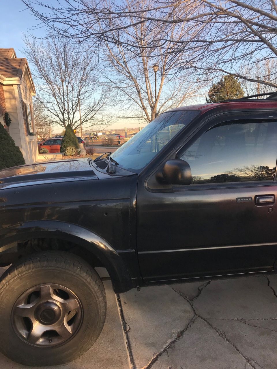 Black Ford Explorer parked on a cracked driveway, side view.