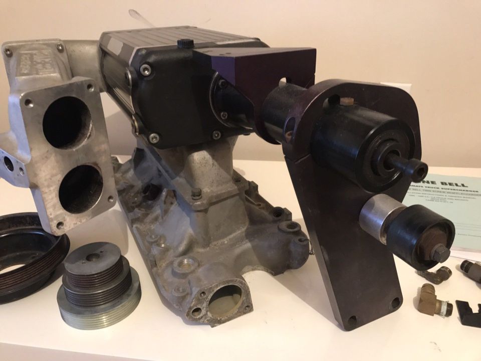 Supercharger assembly with intake manifold, pulleys, and fittings.