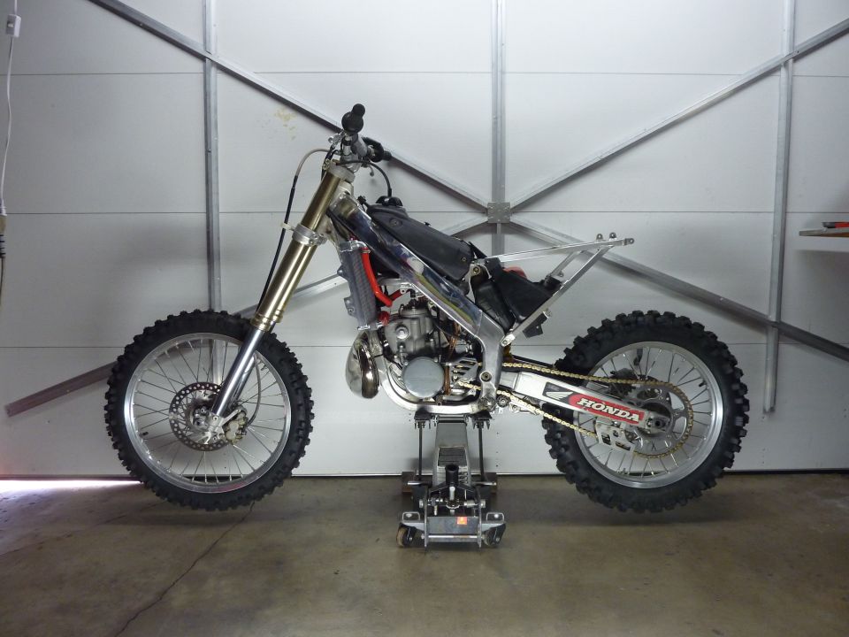 2000 Honda CR250R dirt bike on a stand, side view.