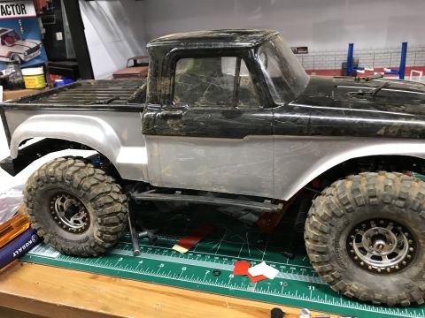 1989 Ford Bronco - This is a model truck with a silver body and large off-road tires, shown from the side.