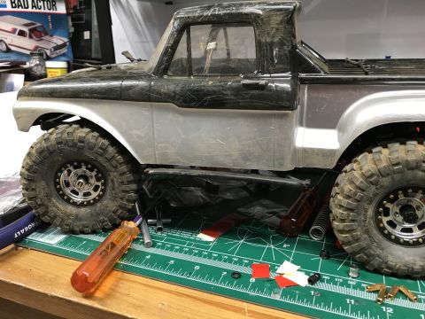 1989 Ford Bronco - RC truck body and parts on a workbench, with tools nearby.