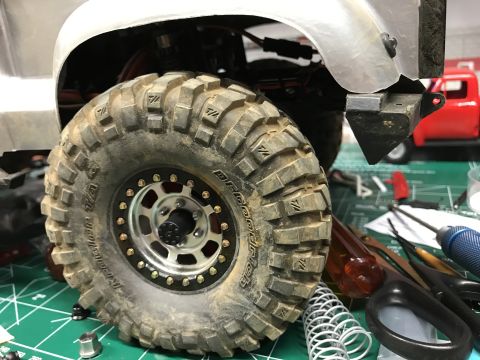 1989 Ford Bronco - A close-up of a model vehicle's tire and fender assembly, with tools scattered around.