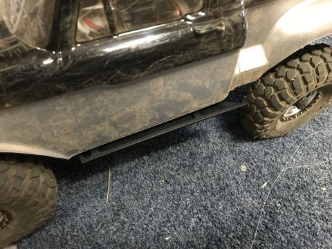 1989 Ford Bronco - Close-up of a toy truck's side panel, running board, and off-road tire.
