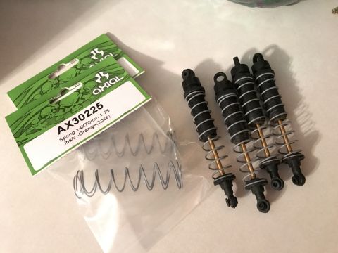 1989 Ford Bronco - RC car shock absorbers and springs are laid out on a surface next to their packaging.