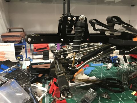 1989 Ford Bronco - Close-up of RC car suspension components and chassis, surrounded by hobby supplies.