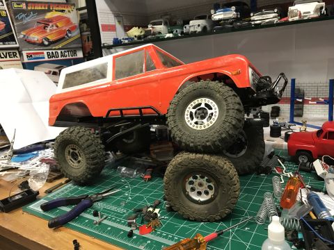 1989 Ford Bronco - A partially assembled model truck sits on a green cutting mat surrounded by tools and parts.