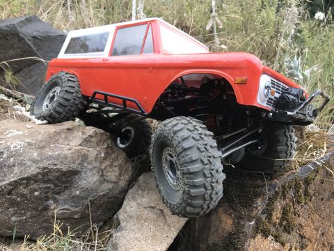 1989 Ford Bronco - This remote-controlled rock crawler features a body resembling an early Ford Bronco, navigating a rocky terrain.