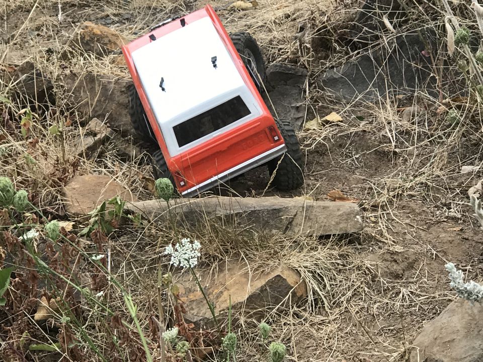 Orange and white RC truck on rocky terrain