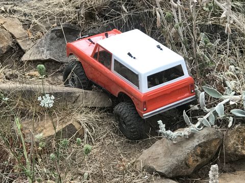 1989 Ford Bronco - RC rock crawler toy truck navigating a rocky obstacle course.