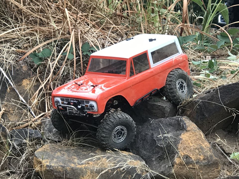 Orange and white RC rock crawler with large tires on rocks