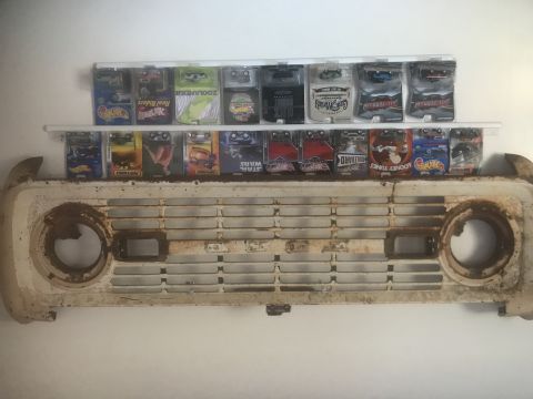 1974 Ford Bronco - A vintage Ford Bronco grille is displayed above a collection of collectible toy cars.