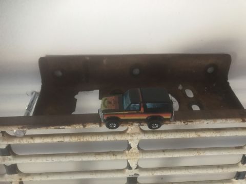 1974 Ford Bronco - A toy Bronco sits on a metal grate, with a Supermotors.net logo visible at the bottom right.