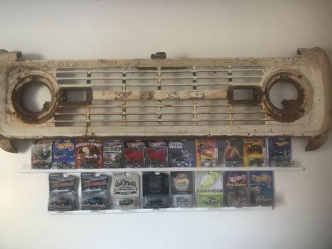 1974 Ford Bronco - A vintage Ford Bronco grille is displayed above a collection of Hot Wheels and other toy cars.