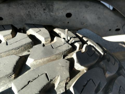 1992 Ford Bronco - A nail is lodged in the tread of a tire, indicating a potential puncture.