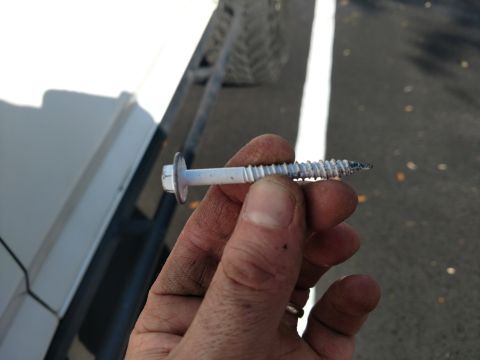 1992 Ford Bronco - A hand holds a large screw, likely for vehicle repair.