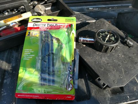 1992 Ford Bronco - A tire repair kit and a tire pressure gauge are laid out, ready for use.