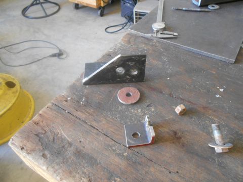 1992 Ford Bronco - Metal brackets and hardware are laid out on a wooden workbench, with a caliper visible in the background.