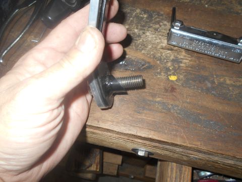 1992 Ford Bronco - A hand holds a metal component with a threaded end over a workbench, with a multi-tool nearby.