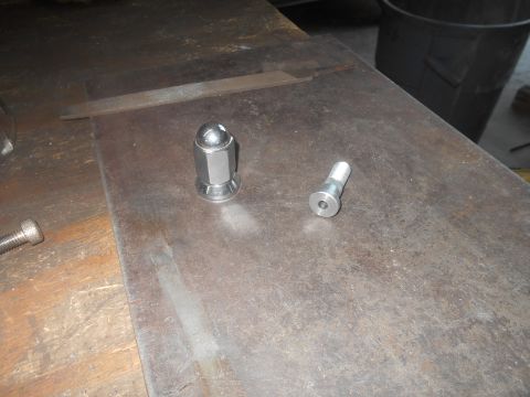 1992 Ford Bronco - Close-up of a lug nut and a wheel stud resting on a metal surface.