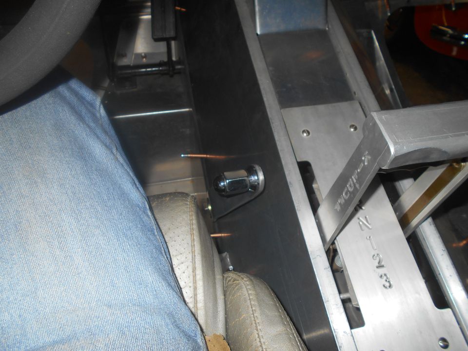 Close-up of a vehicle's interior showing a custom shifter mechanism and part of a driver's leg in jeans