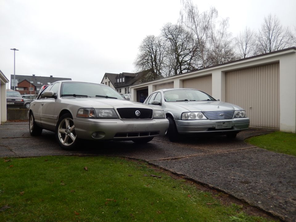 Silver Mercury Grand Marquis and Ford Falcon parked outside garages
