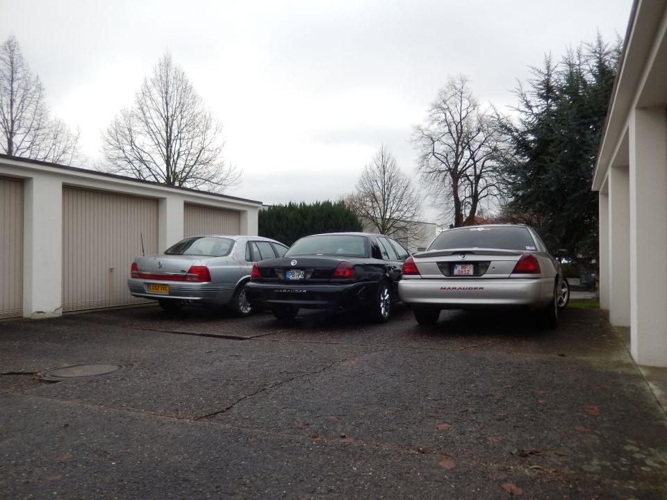 Silver sedan with 'MARAUDER' text on the rear, parked next to a black sedan and a silver sedan