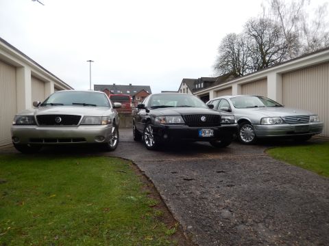 1999 Ford Fairlane - Three sedans, including a silver 2003 Mercury Grand Marquis, are parked in front of garages.