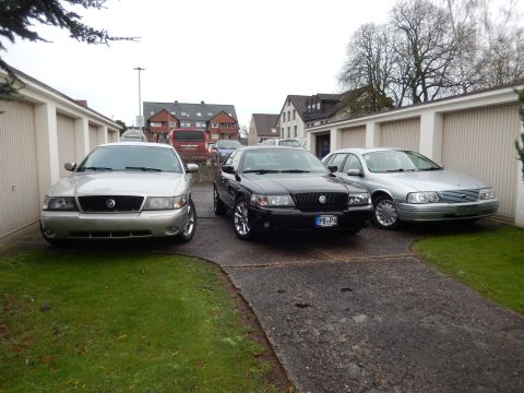 1999 Ford Fairlane - Three sedans, including two Mercury models and a Ford, are parked in a residential driveway.