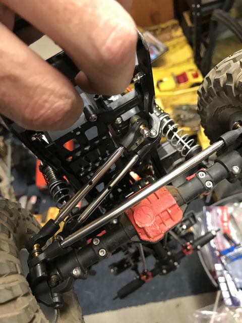 1989 Ford Bronco - A person's hand is visible, adjusting the suspension system of a detailed RC car model.