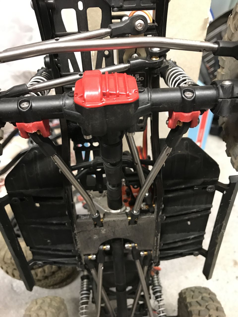 RC car chassis with red differential cover and silver suspension arms