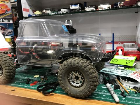 1989 Ford Bronco - RC car body and chassis assembly with tools and decals visible on a workbench.
