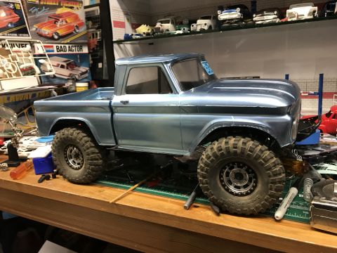 1989 Ford Bronco - Model truck with custom wheels and tires on a cluttered workbench.