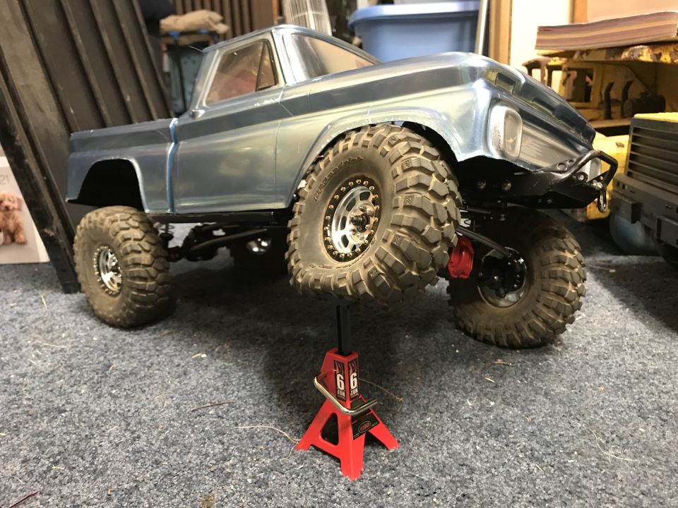 Blue pickup truck body on red jack, front quarter view