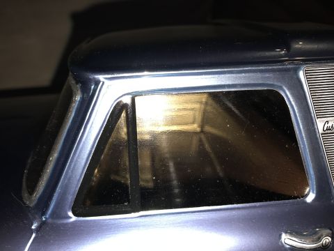 1989 Ford Bronco - Close-up of a blue pickup truck's side window and grille, indicating it is a 'Custom' model.