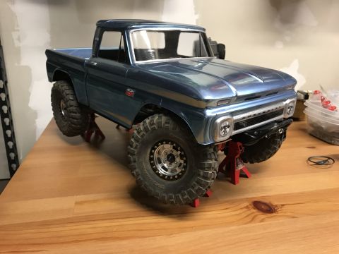 1989 Ford Bronco - A model pickup truck, likely a 1966 Chevrolet C10, is displayed on jack stands.