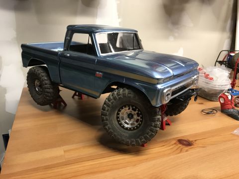 1989 Ford Bronco - A blue 1966 Chevrolet C10 pickup truck model is elevated on red jack stands on a wooden surface.
