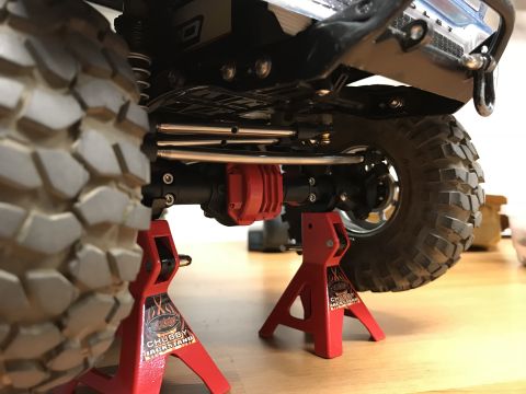 1989 Ford Bronco - The underside of a remote control car is elevated on jack stands, revealing its suspension components and off-road tires.