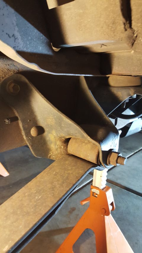 1996 Ford Bronco - The underside of a vehicle shows a leaf spring assembly being worked on, with an orange jack stand providing support.
