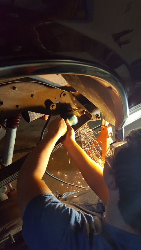 1996 Ford Bronco - A person grinds metal on the underside of a vehicle, with sparks flying and red coil springs visible.