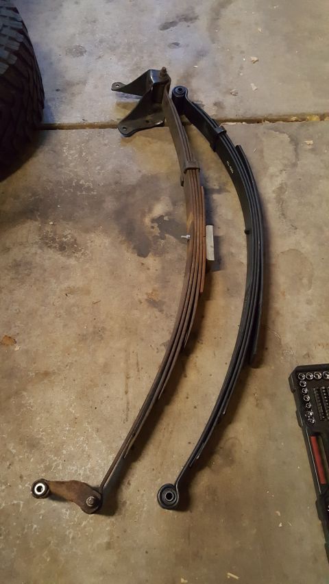 1996 Ford Bronco - Leaf springs and a tire are shown on a concrete floor, possibly for a vehicle repair or upgrade.