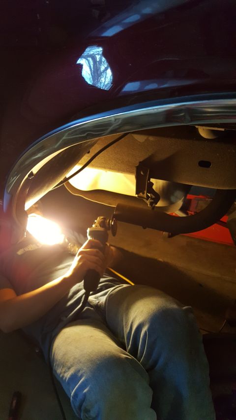 1996 Ford Bronco - Working on the undercarriage of a vehicle, cutting an exhaust pipe with a grinder.